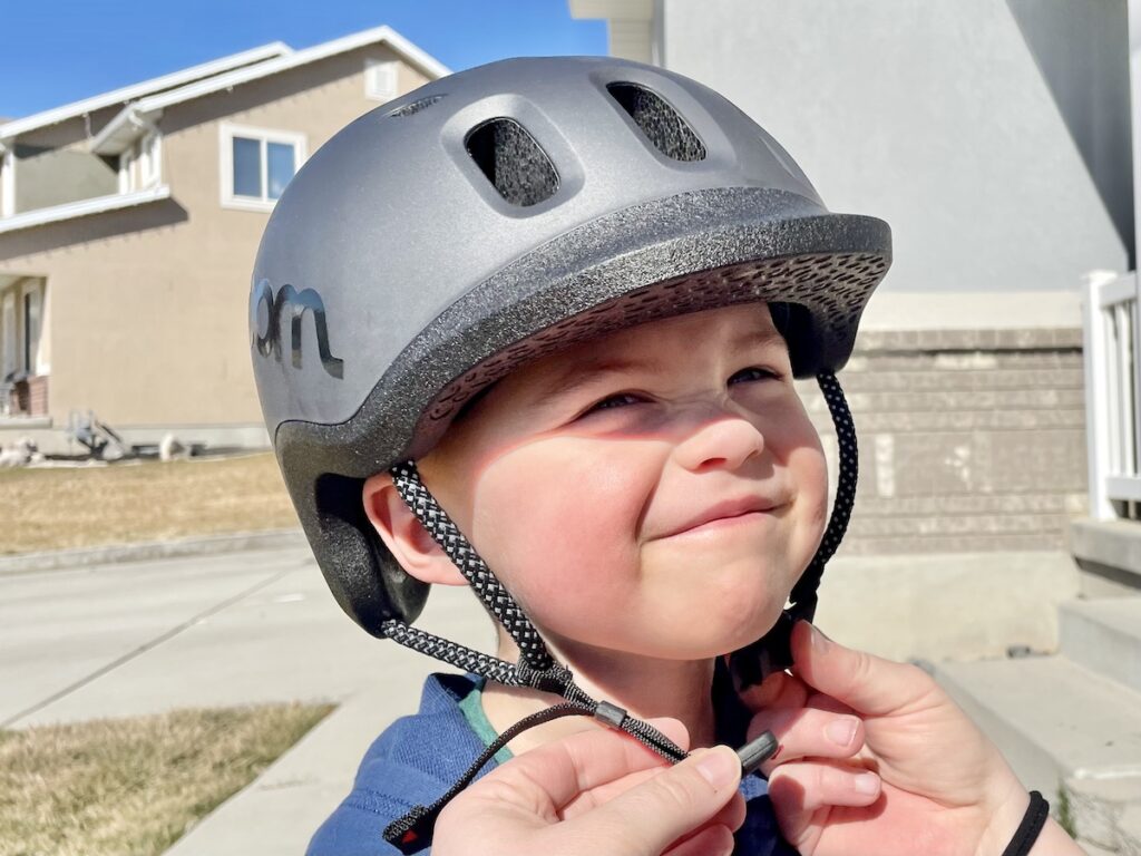 dziecko stoi na jednej nodze na rowerku balance bike w ogrodzie