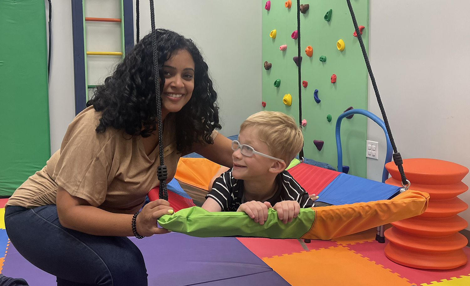 chłopiec dmucha balonik podczas ćwiczeń oddechowych z terapeutką obok