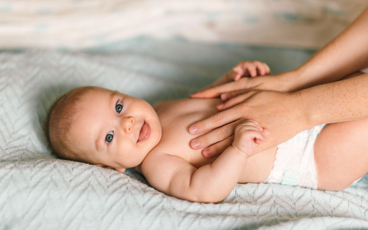 olejkiem natłuszczone ręce terapeuty masują jelita brzucha niemowlęcia